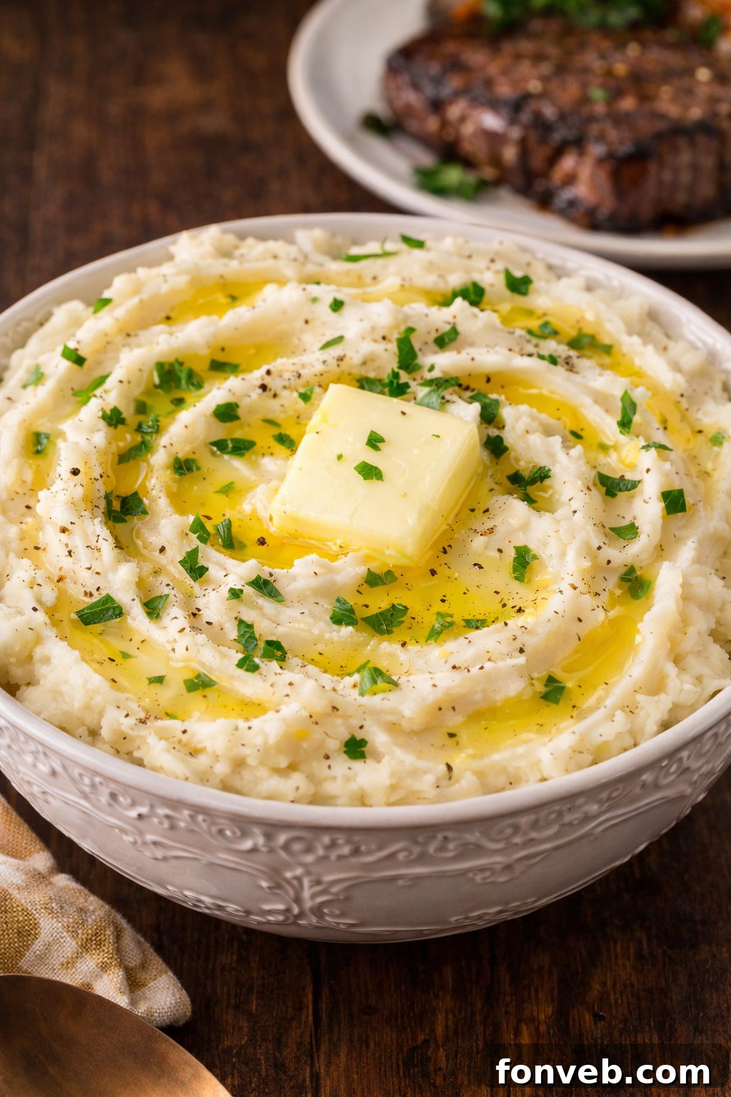Effortless Creamy Garlic Mashed Potatoes 2 Garlic mashed potatoes in a white bowl on a dark wood table