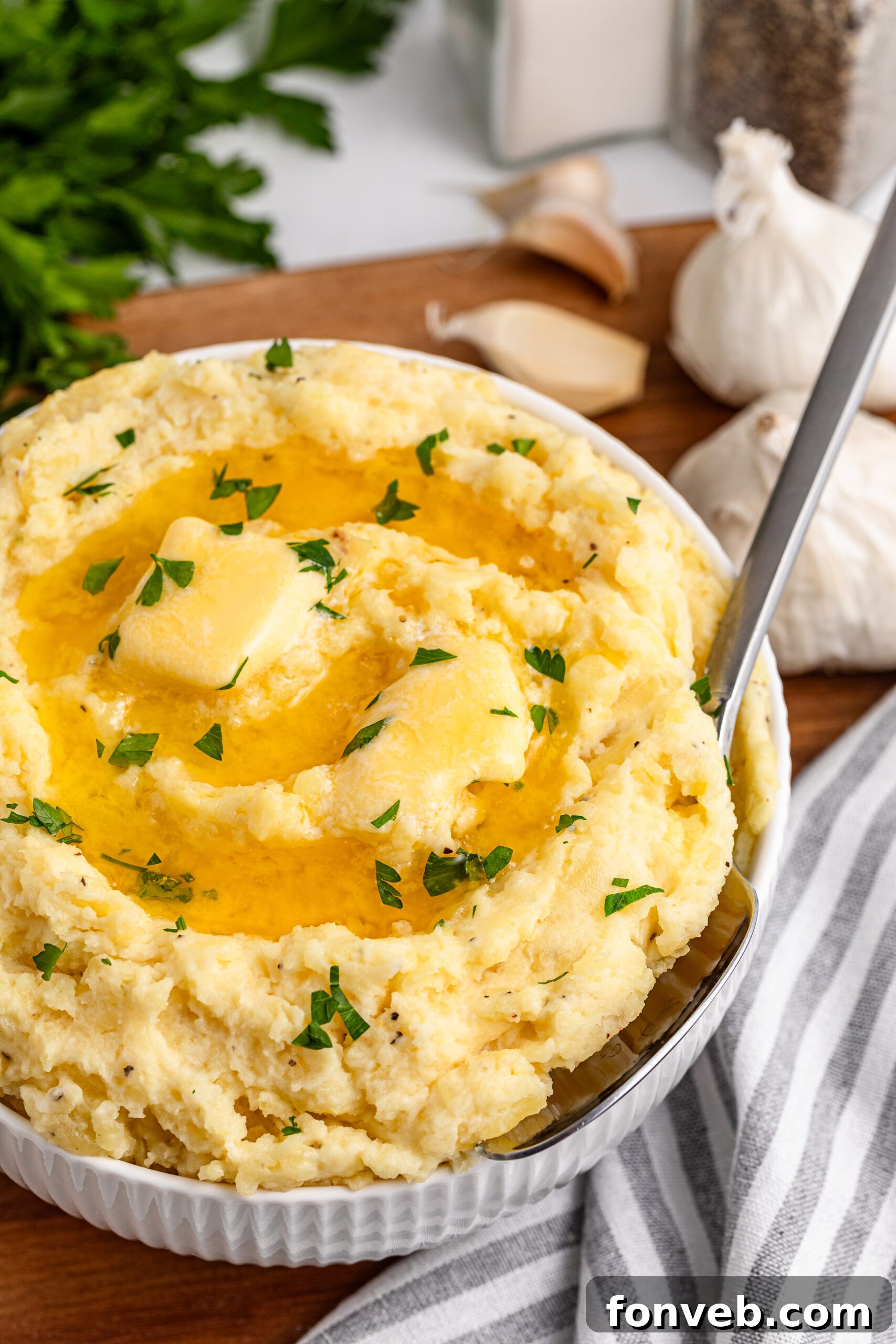 Effortless Creamy Garlic Mashed Potatoes 3 Garlic mashed potatoes in a white bowl on a dark wood table