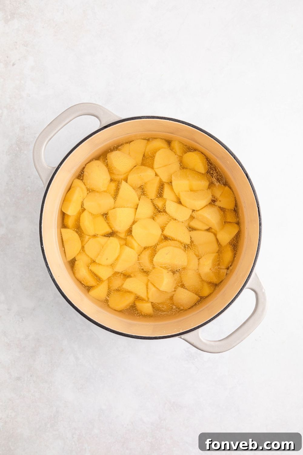 Effortless Creamy Garlic Mashed Potatoes 7 peeled and diced potatoes in a pot with water sitting on the table