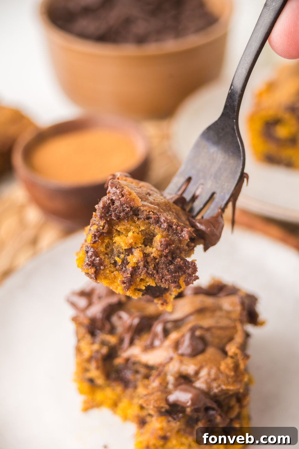 Brown Butter Pumpkin Chocolate Chip Bar on a white plate with a fork with a bite taken out of the bar on the fork 