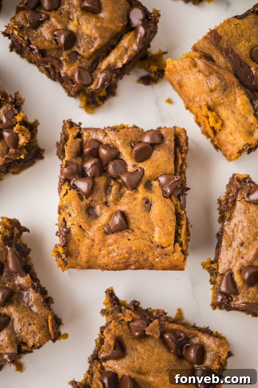square slices of Brown Butter Pumpkin Chocolate Chip Bars placed around the table 