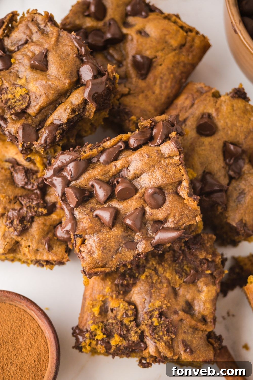 Brown Butter Pumpkin Chocolate Chip Bars stacked on top of one another on a white table 