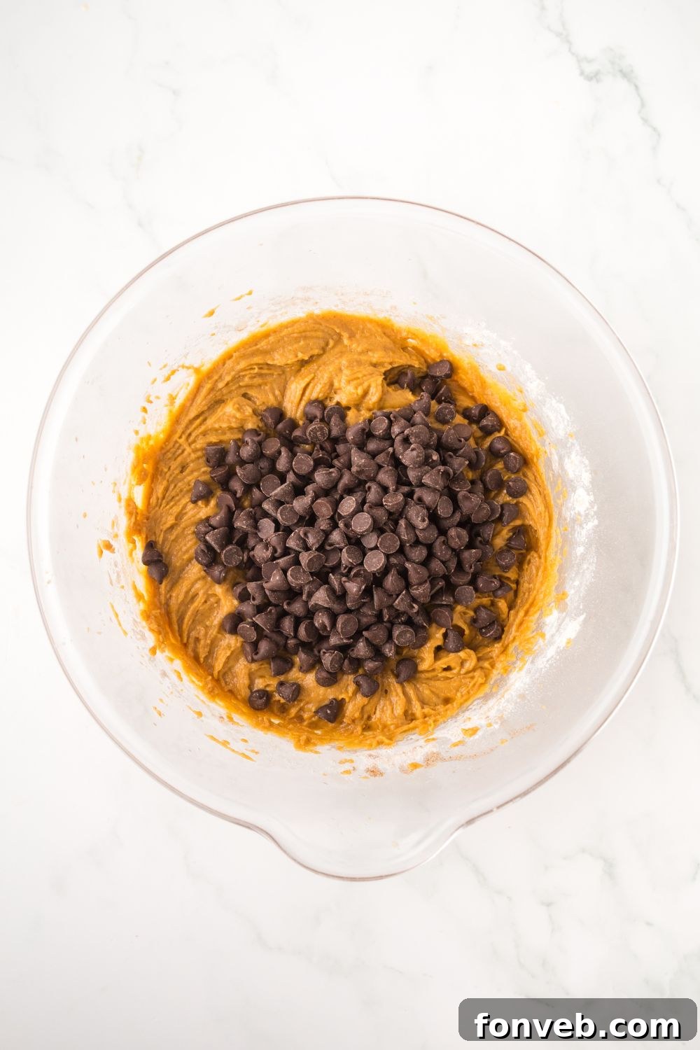 pumpkin bar batter in a glass bowl topped with chocolate chips sitting on a white table 