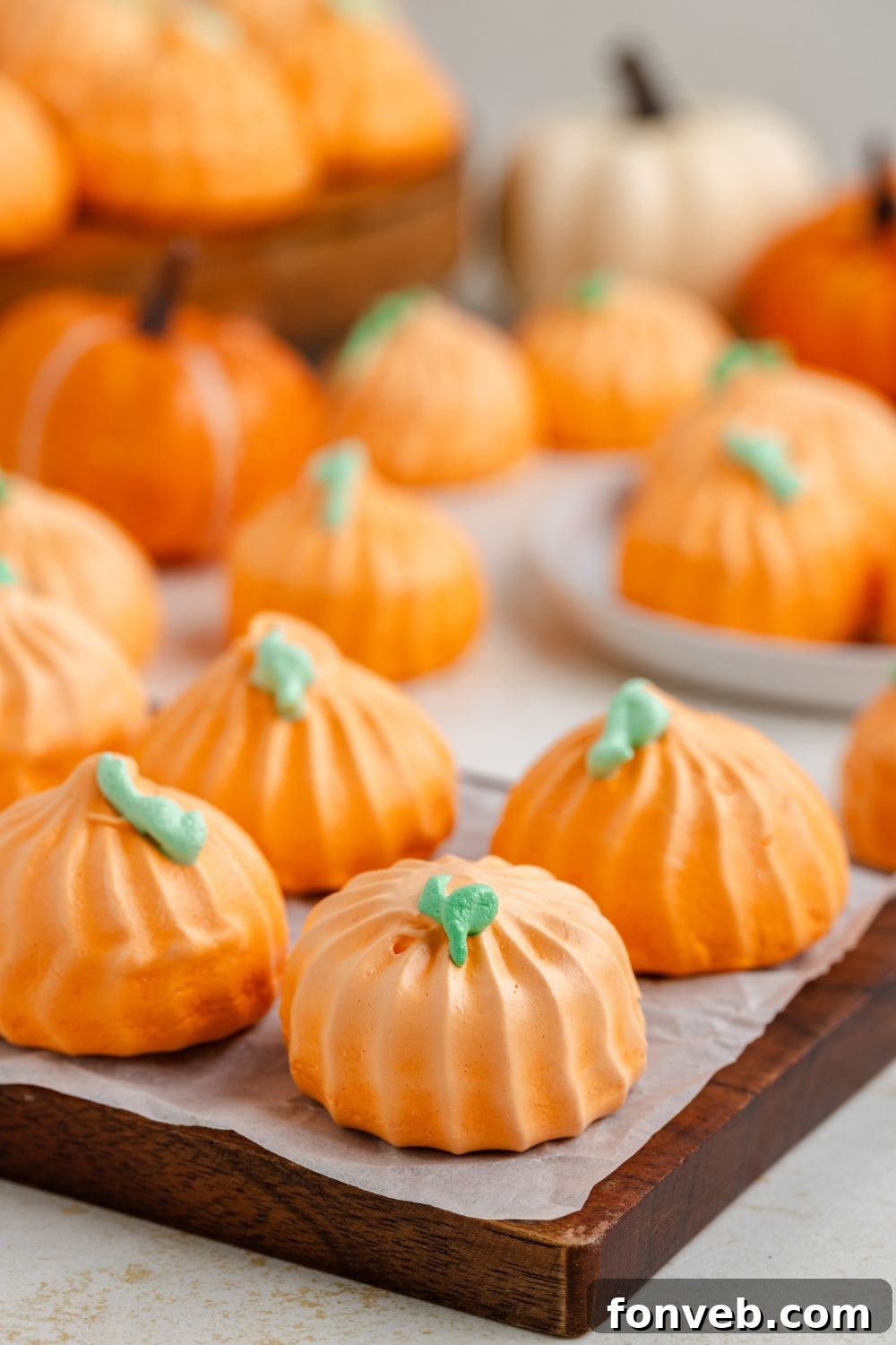 wooden serving tray with some Pumpkin Meringues placed on it, and more scattered around the table on plates and on trays 
