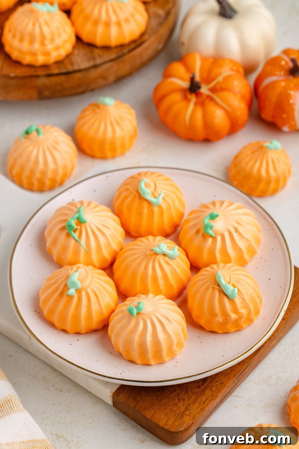 Pumpkin Meringues on a white plate on table with more cookies around and a few small pumpkins 