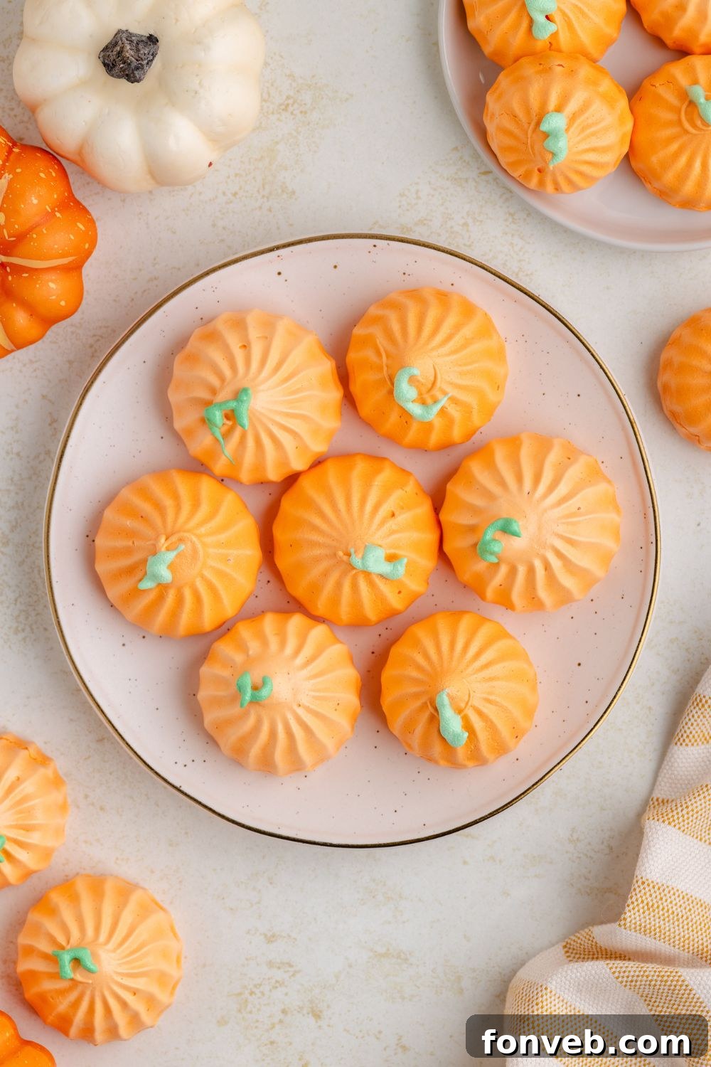 looking down at table with a plate in center with Pumpkin Meringues on it, and then more cookies in bunches around table and mini pumpkins 