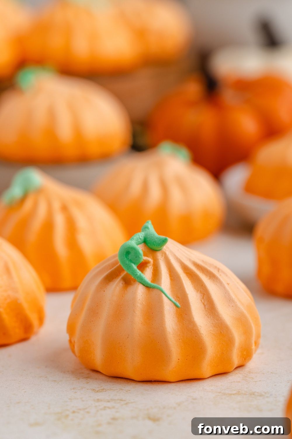 Pumpkin Meringues placed around table in a single row with faux mini pumpkins on table as well 