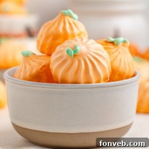 Pumpkin Meringues placed in a white bowl on table with more meringues behind it on table