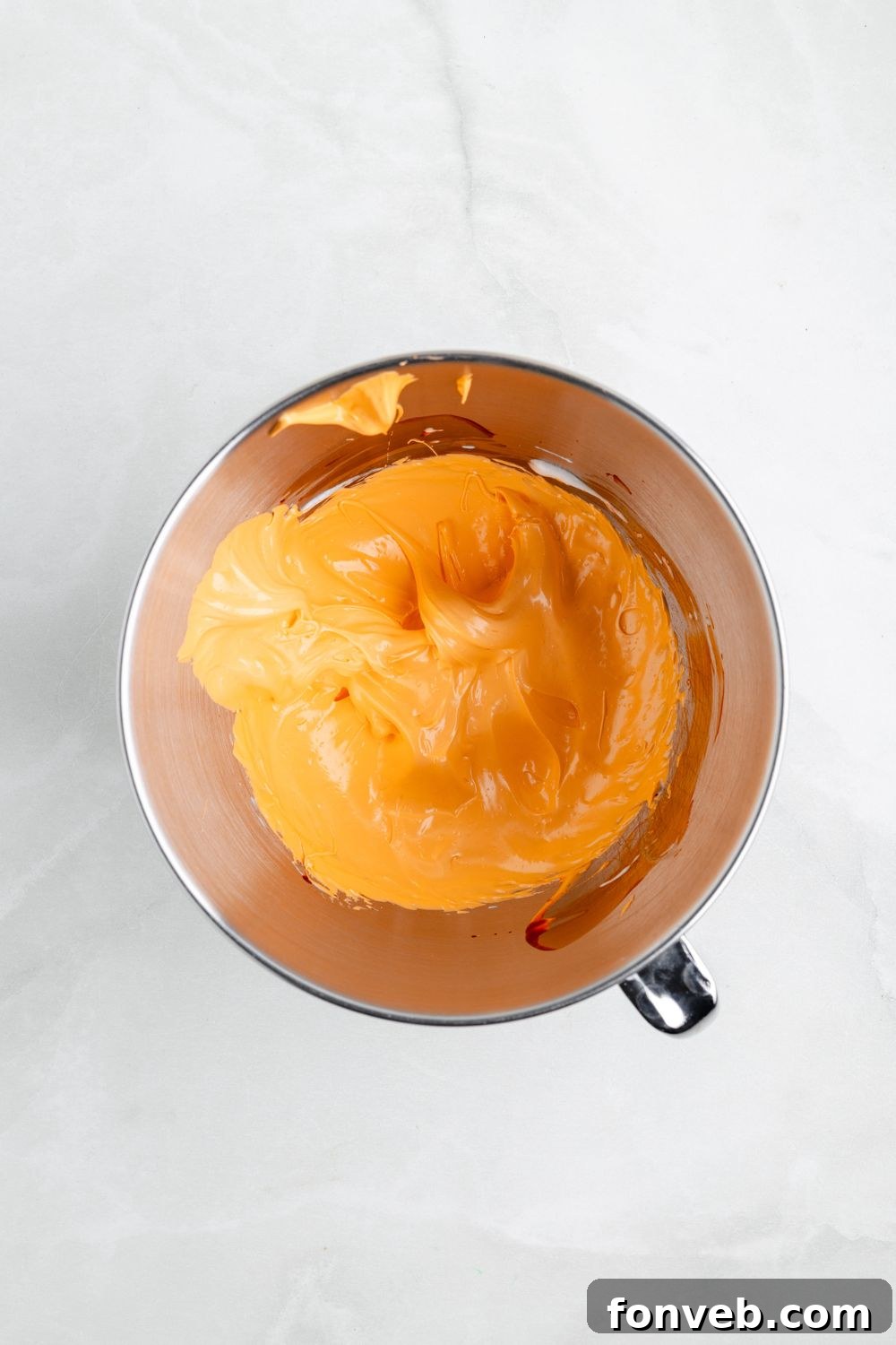 metal mixing bowl full of orange meringue 
