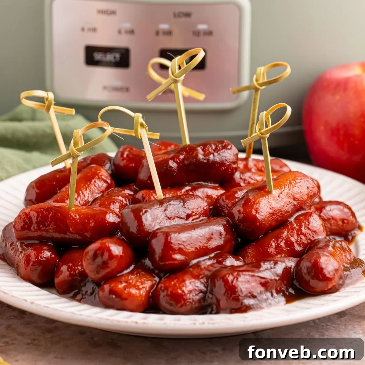Sweet and Tangy Crockpot Apple Butter Smokies 2 Crockpot Apple Butter BBQ Little Smokies on a white plate with toothpicks in it, with a slow cooker behind it on the table