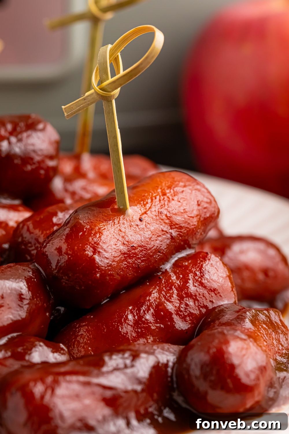 Sweet and Tangy Crockpot Apple Butter Smokies 16 Apple Butter BBQ Little Smokies on a plate with toothpicks in a few and an apple and crockpot sitting in the background