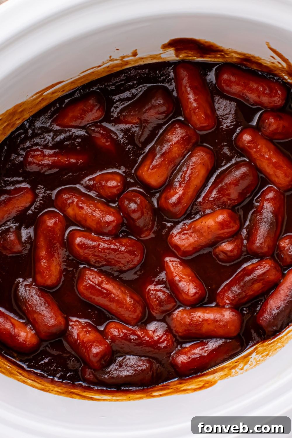 Sweet and Tangy Crockpot Apple Butter Smokies 19 overhead look of a white crockpot full of bbq sauce smokies