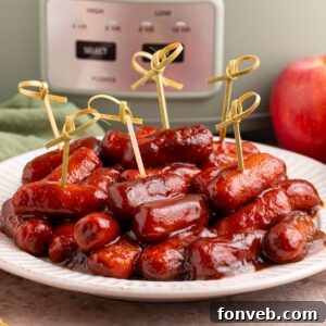 Sweet and Tangy Crockpot Apple Butter Smokies 21 Crockpot Apple Butter BBQ Little Smokies on a white plate with toothpicks in it, with a slow cooker behind it on the table