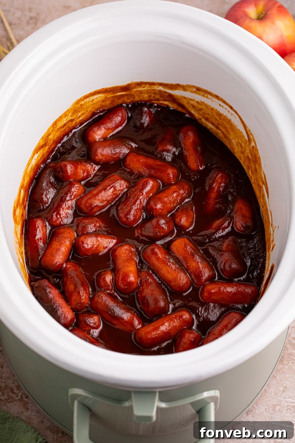 Sweet and Tangy Crockpot Apple Butter Smokies 4 looking down on a white crockpot full of apple butter little smokies