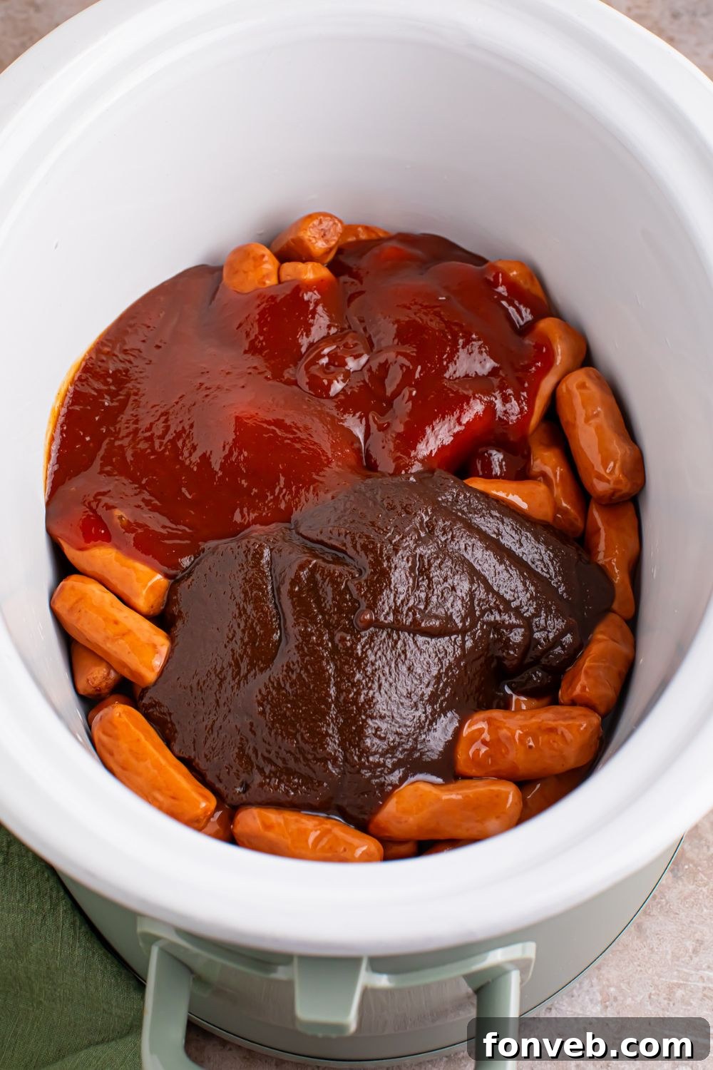 Sweet and Tangy Crockpot Apple Butter Smokies 6 lil smokies with sauces on top in a white crockpot on the table