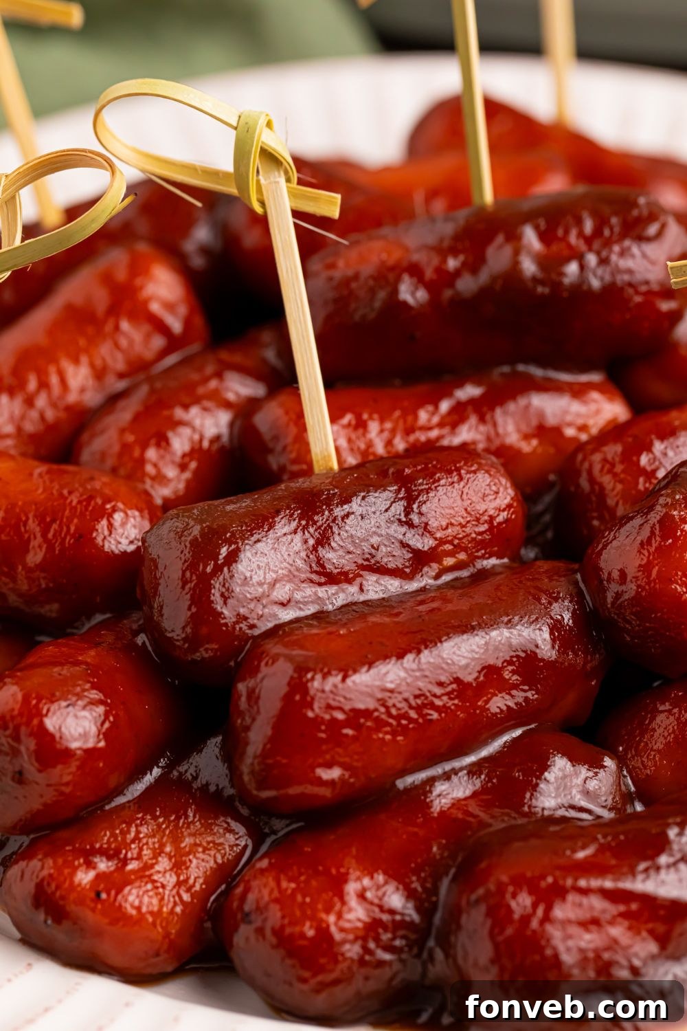 Sweet and Tangy Crockpot Apple Butter Smokies 8 toothpicks poked into saucy lil smokies on a white platter
