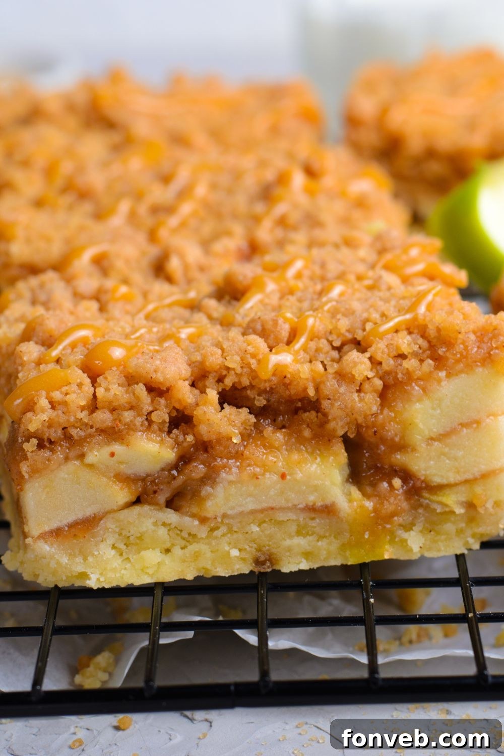 close up of a sliced Caramel Apple Pie Bar on a cooling rack with a green apple to the side