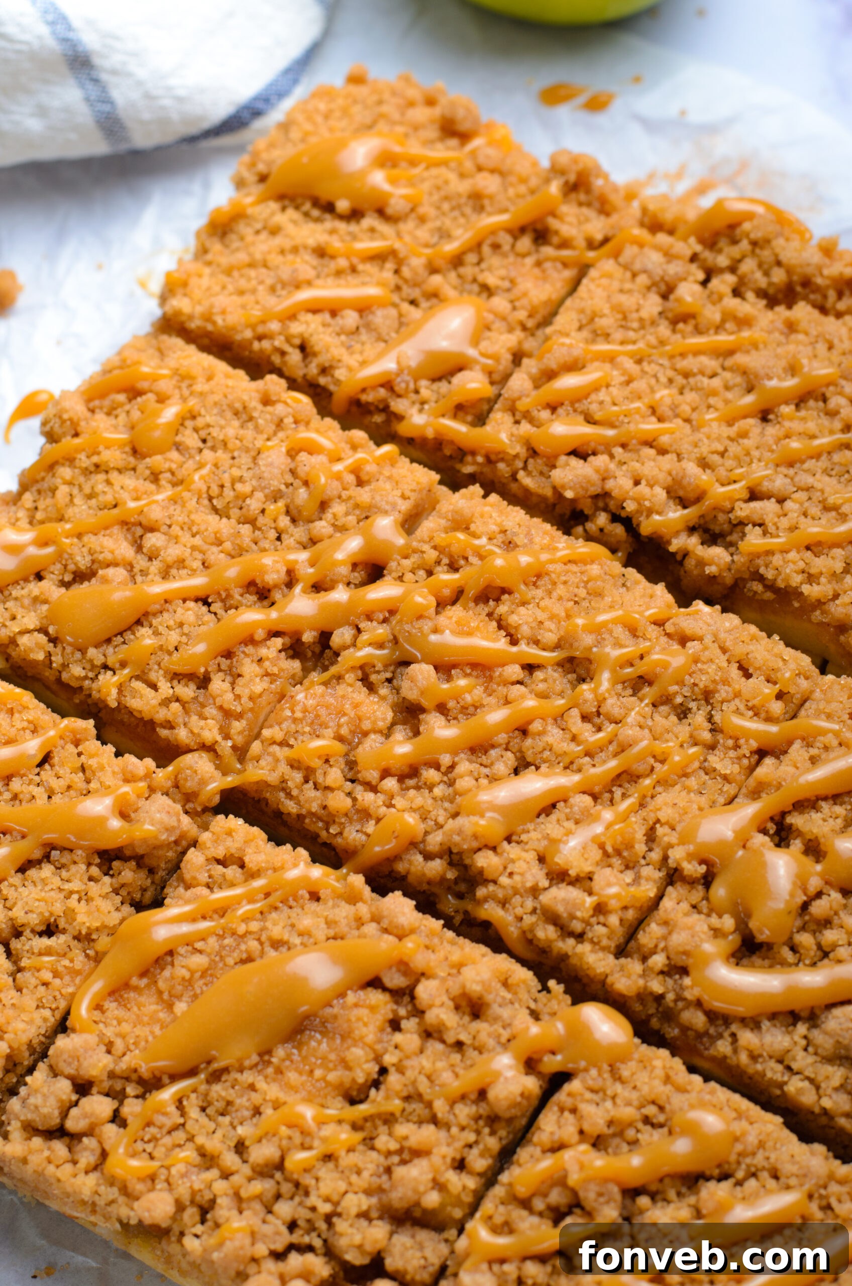 Up close shot of the Caramel Apple Pie Bars cut into squares with a drizzle of caramel sauce on top sitting on a table