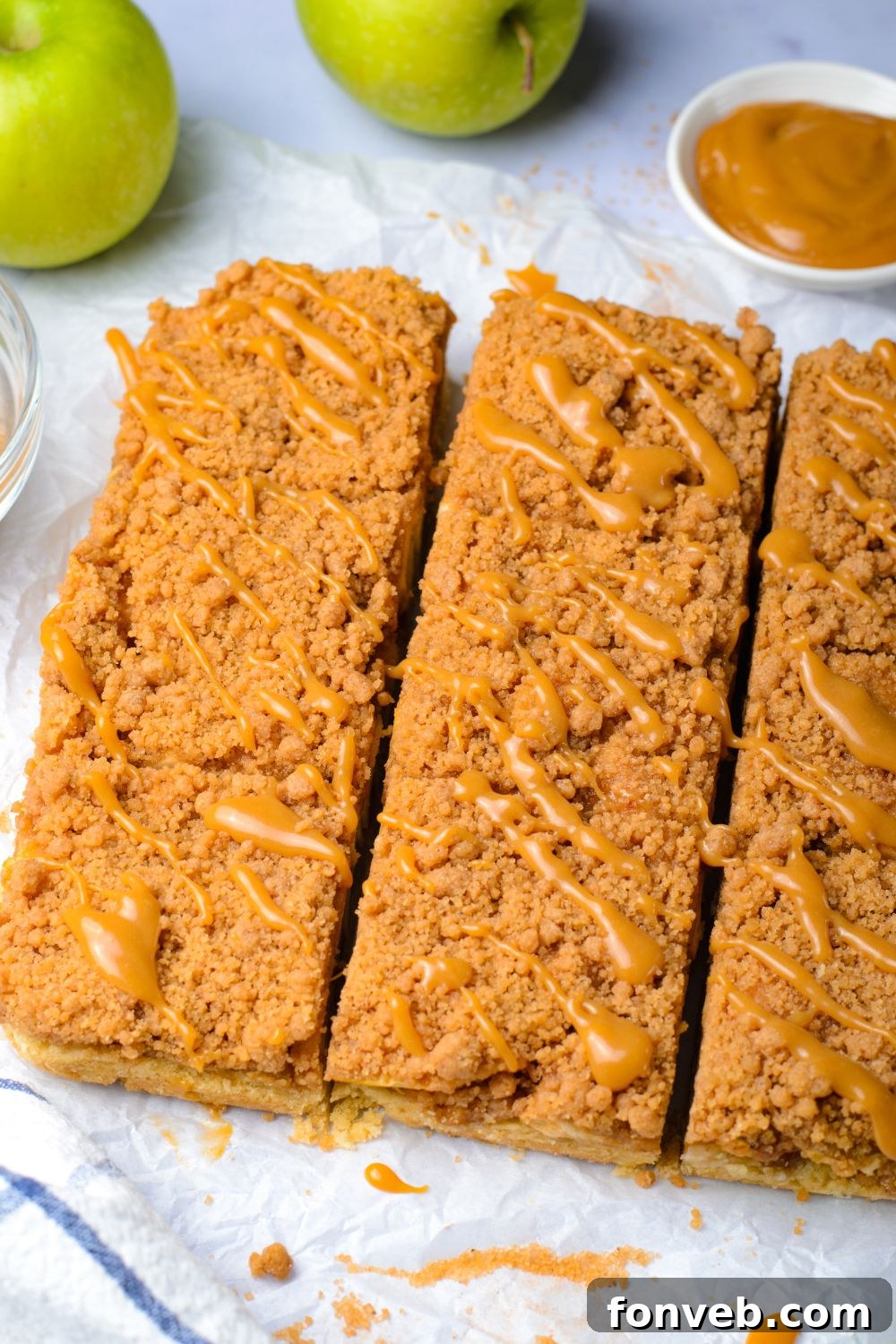 Caramel Apple Pie Bars cut into squares with a drizzle of caramel sauce on top sitting on a table