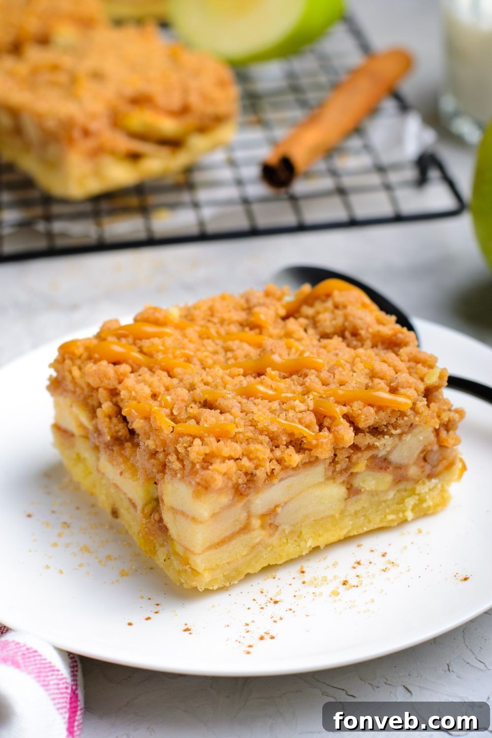 Caramel Apple Pie Bar on a plate with a spoon behind it on a white table