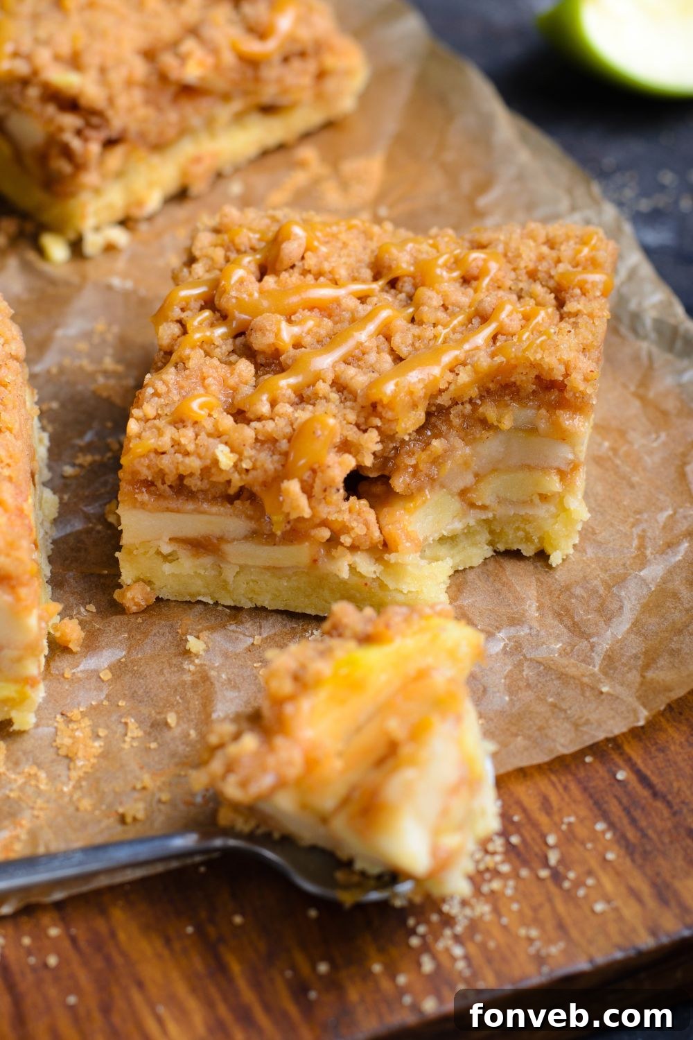 Caramel Apple Pie Bar sliced into a square with a bite taken out and placed on a spoon in front of the bar