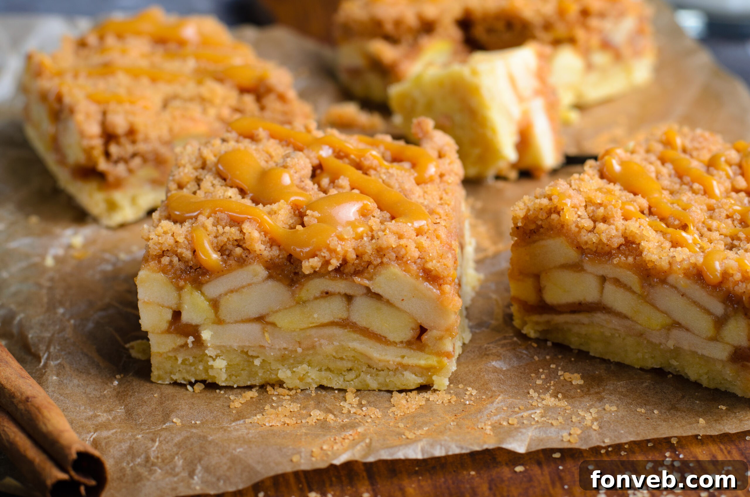 Side view of the Caramel Apple Pie Bars placed on brown parchment paper with cinnamon sticks next to them