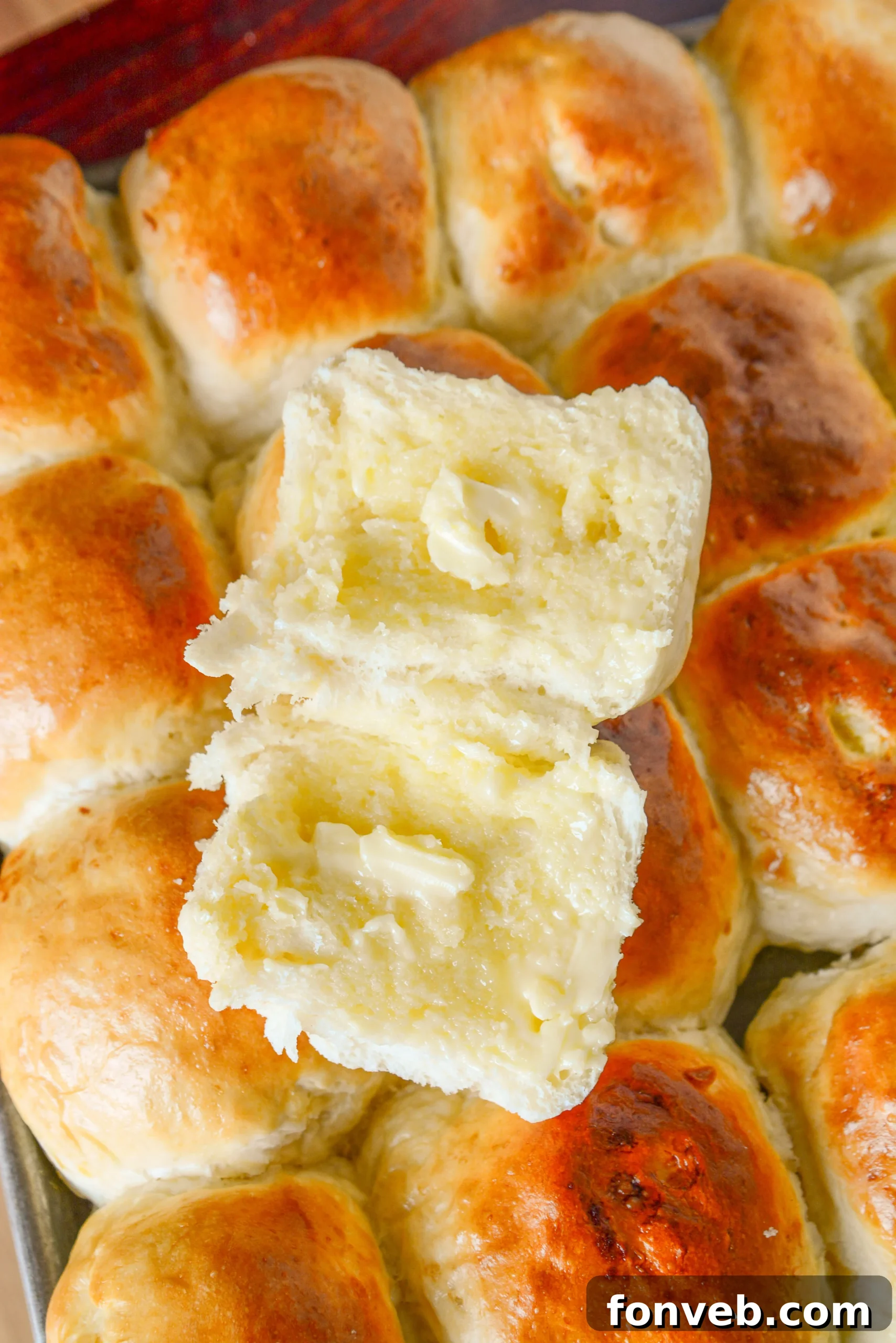 Freshly baked golden brown dinner rolls arranged in a baking dish.