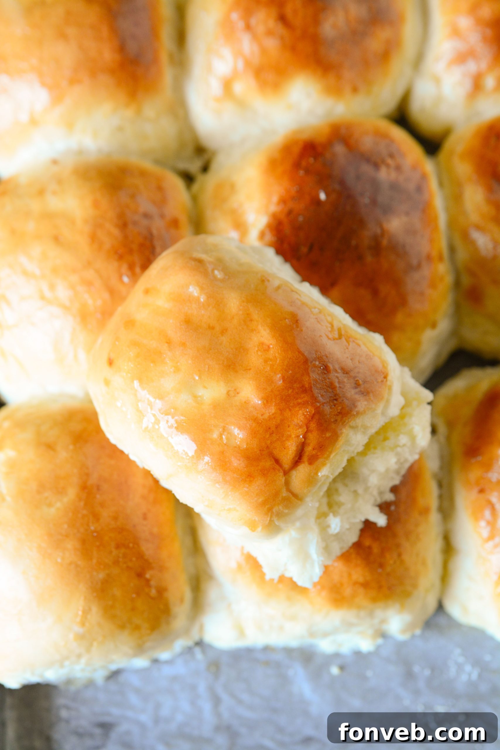 A close-up of several homemade dinner rolls, showcasing their golden crust and fluffy appearance.