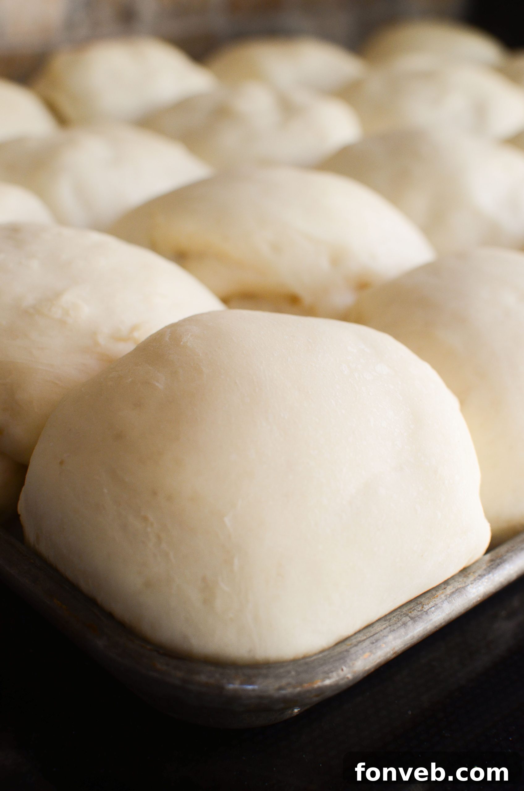 Hand-kneading a soft, risen dough in a large mixing bowl.
