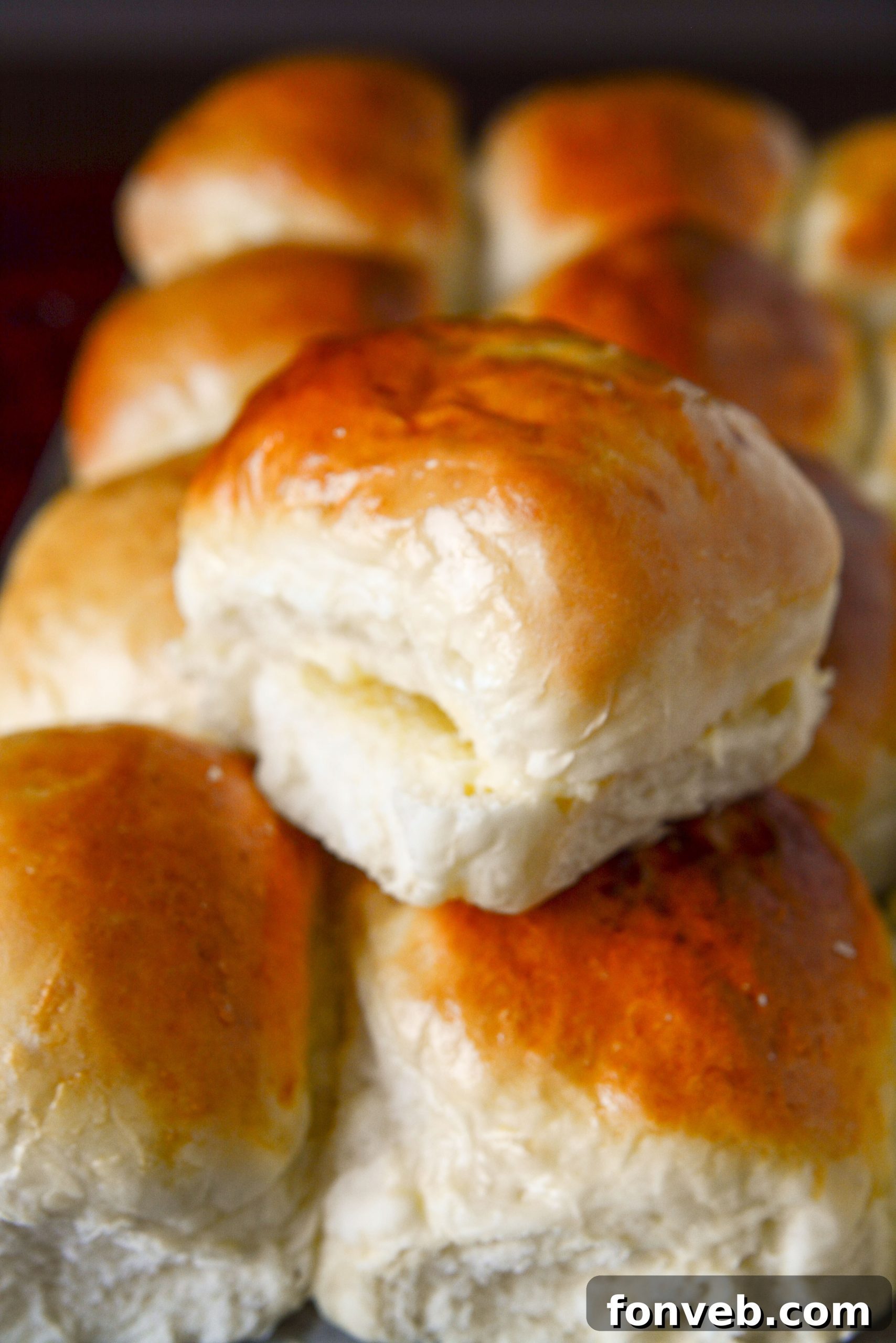 A collection of fluffy, homemade dinner rolls arranged artfully on a wooden board.