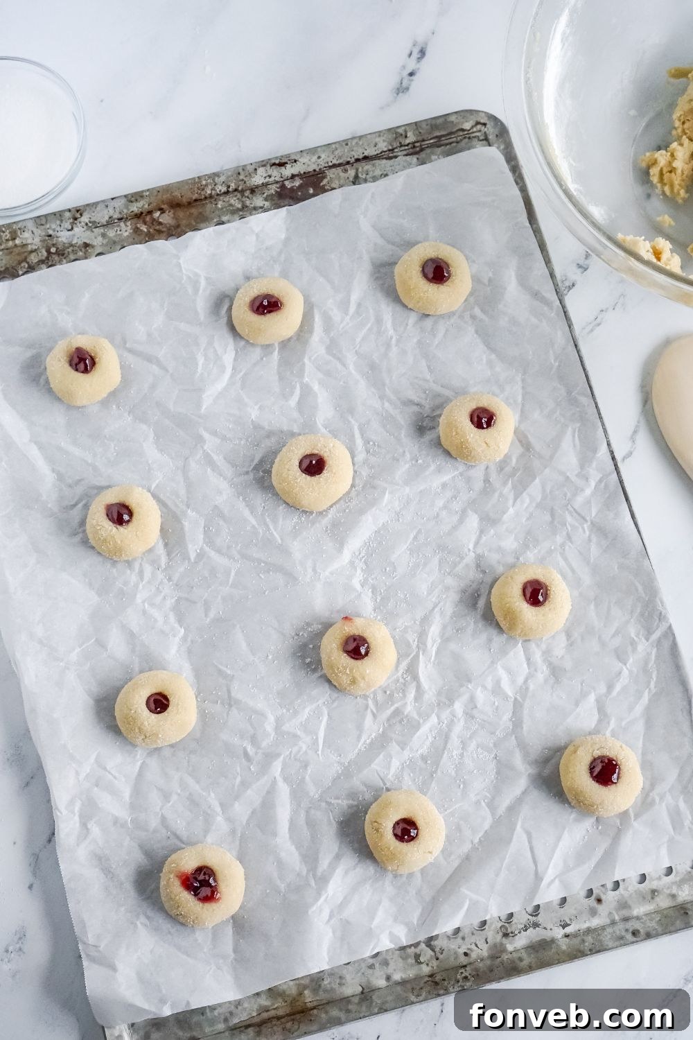 raw Raspberry Thumbprint Cookie dough placed on a baking sheet with parchment paper