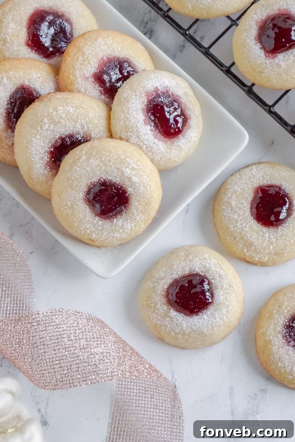 Raspberry Thumbprint Cookies on a rectangle tray with ribbon twirled to side