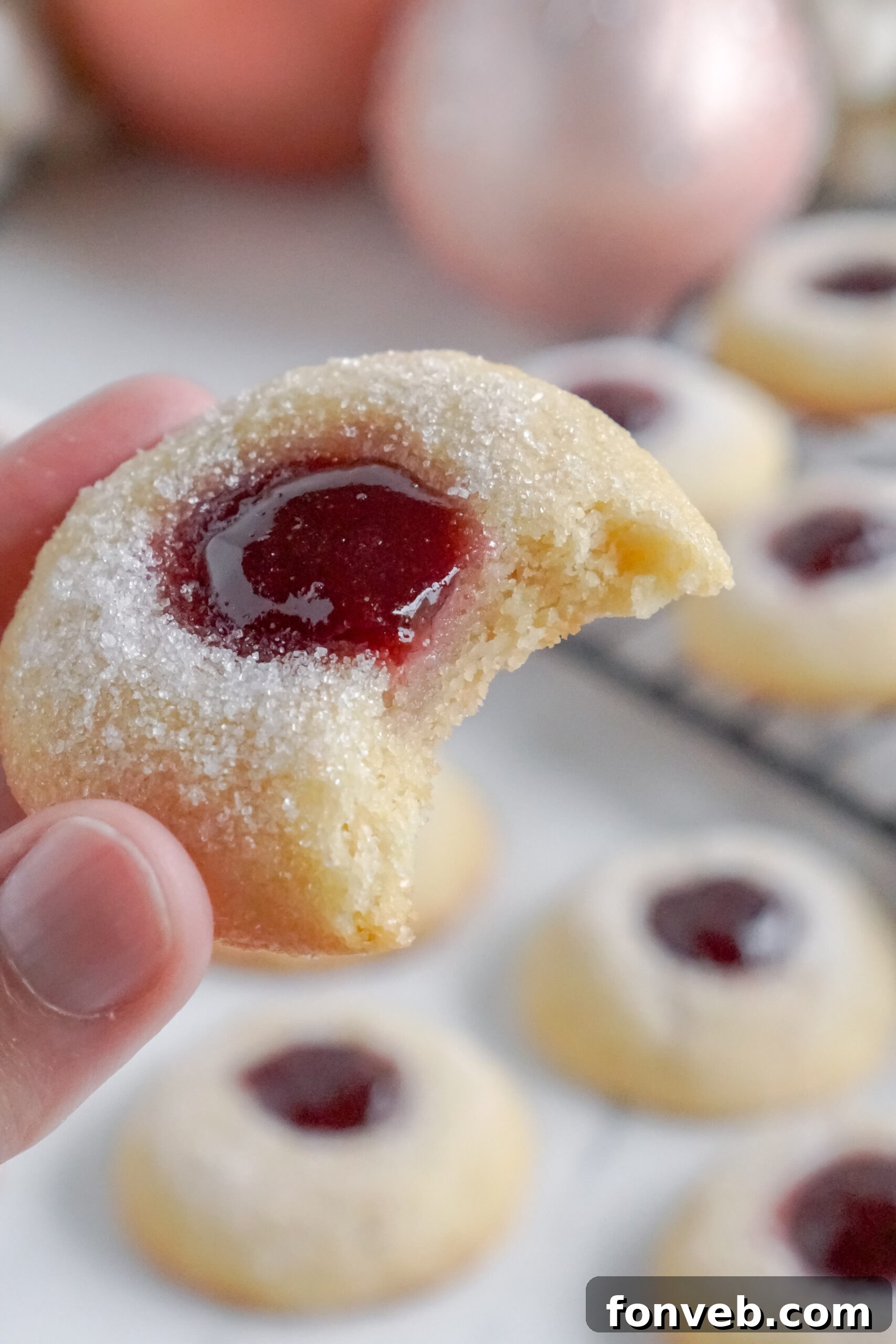 Raspberry Thumbprint Cookie with a bite missing being held up