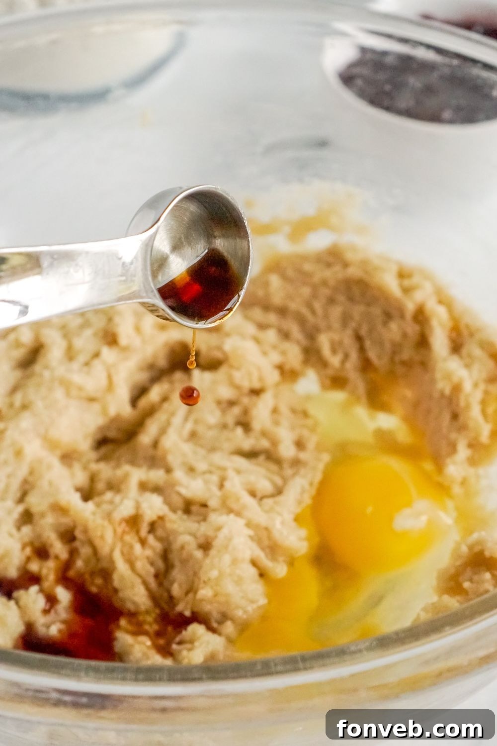 vanilla pouring into a bowl of cookie dough