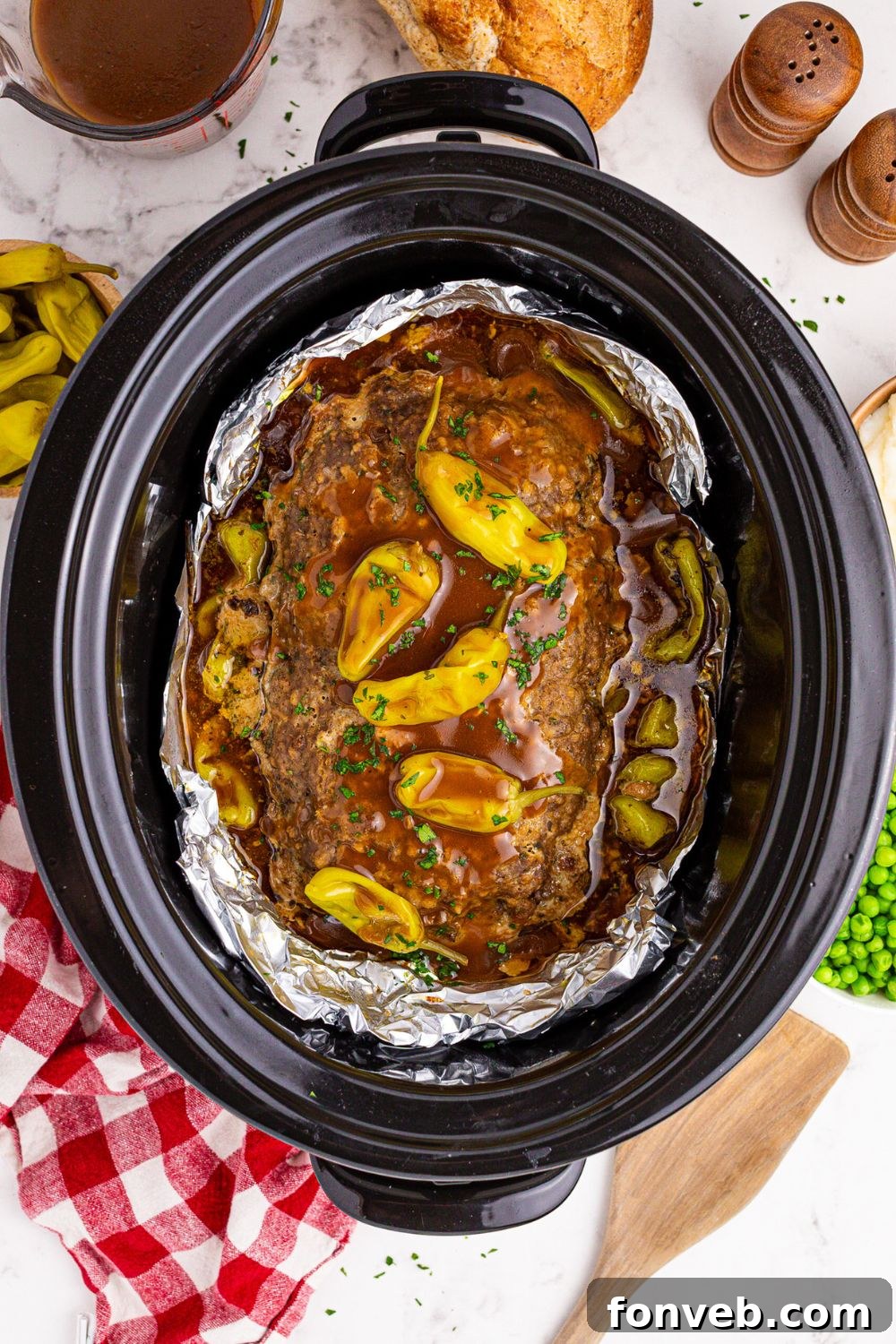 looking down on table to see Crockpot Mississippi Meatloaf with a red checkered towel to side