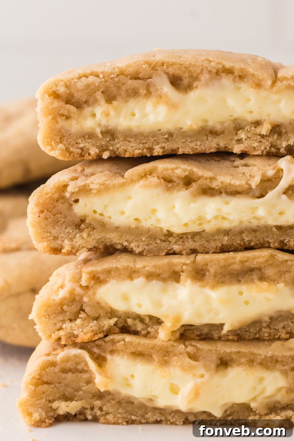 soft stuffed cheesecake cookies stacked on top of one another and cut in half to show the filling