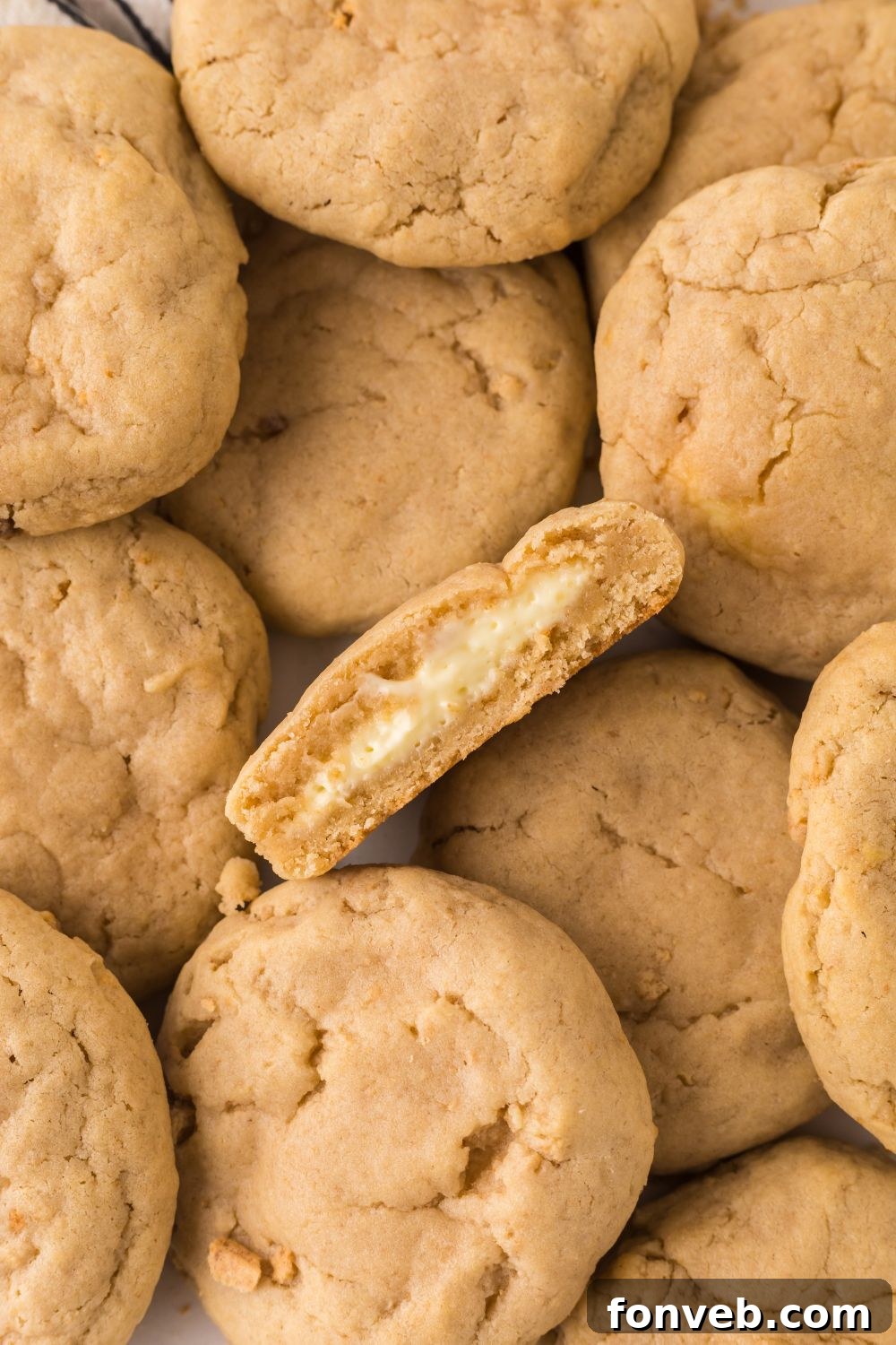 New York cheesecake cookies spread out on table with one cut in half and tilted on side to show the cheesecake filling