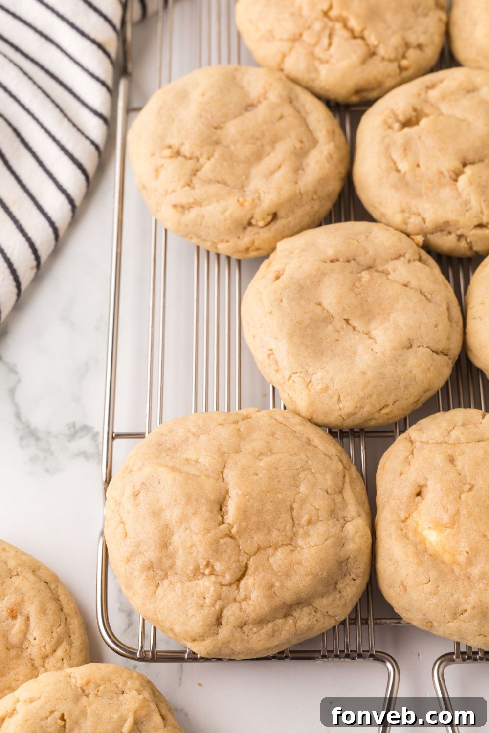 New York cheesecake cookies on a metal cooling rack with a towel to side of tray