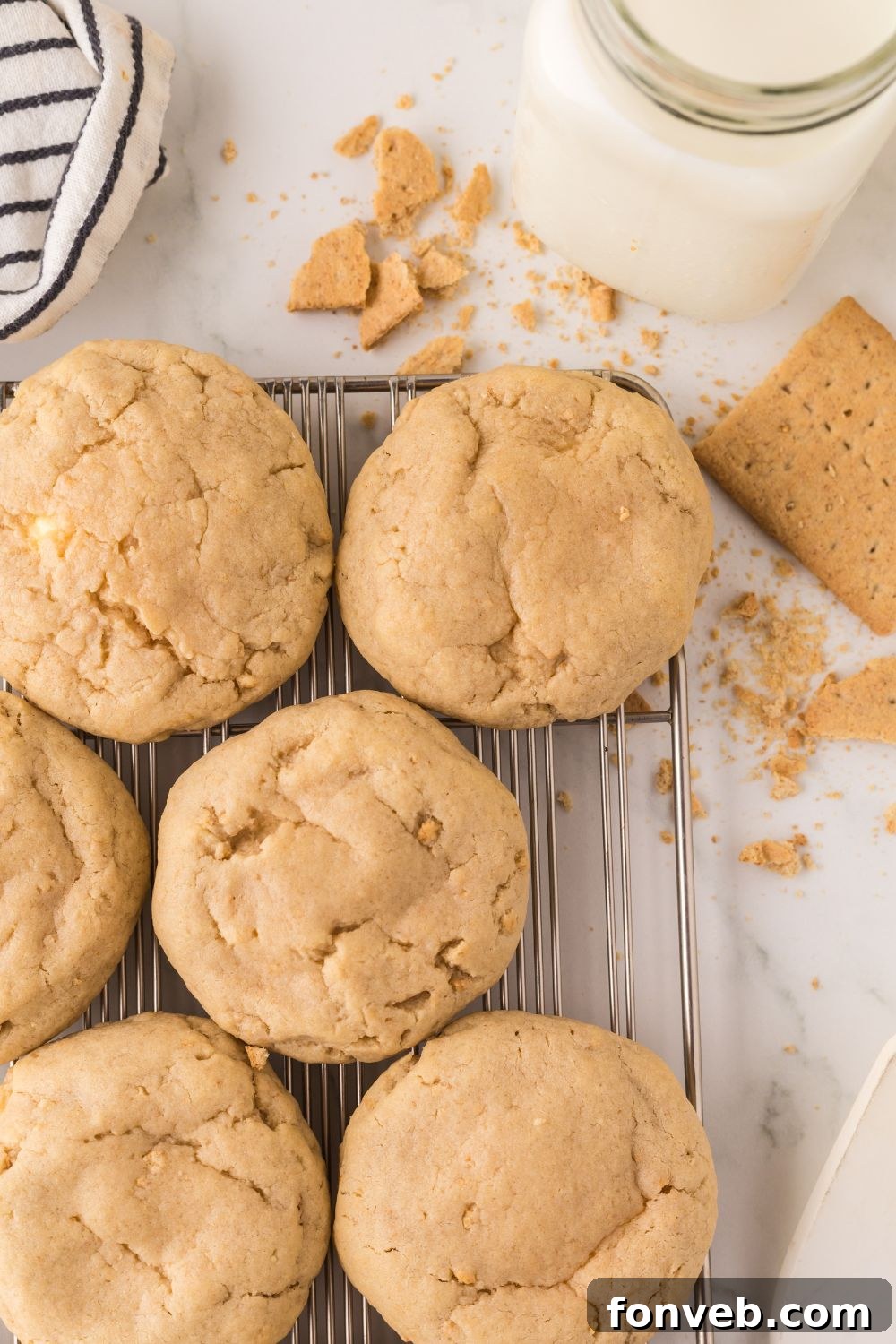 New York cheesecake cookies on a cooling rack with some graham crackers around table and crumbs