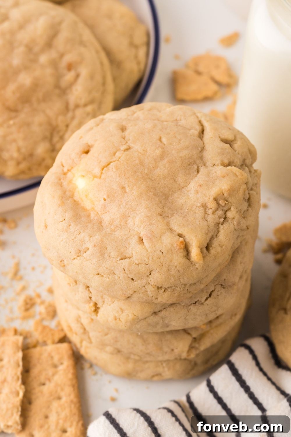 New York cheesecake cookies in a stack with more on a plate with a bottle of milk to the side