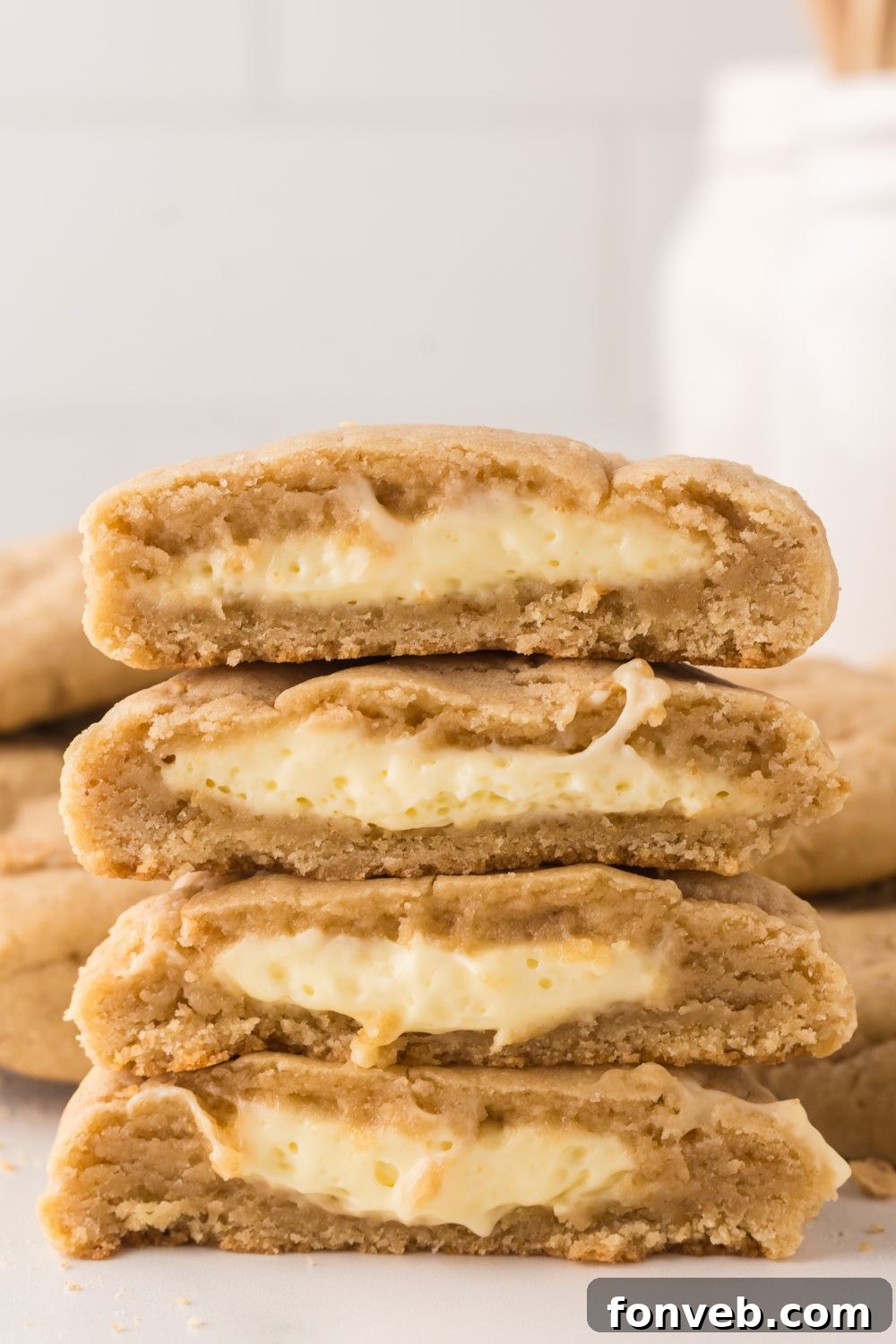 two cookies cut in half with cheesecake filling in each cookie on marble counter