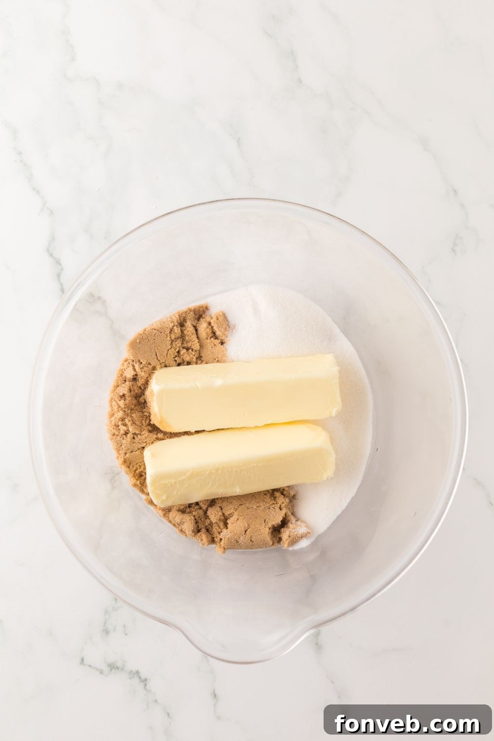 butter and sugars in a glass bowl on marble counter