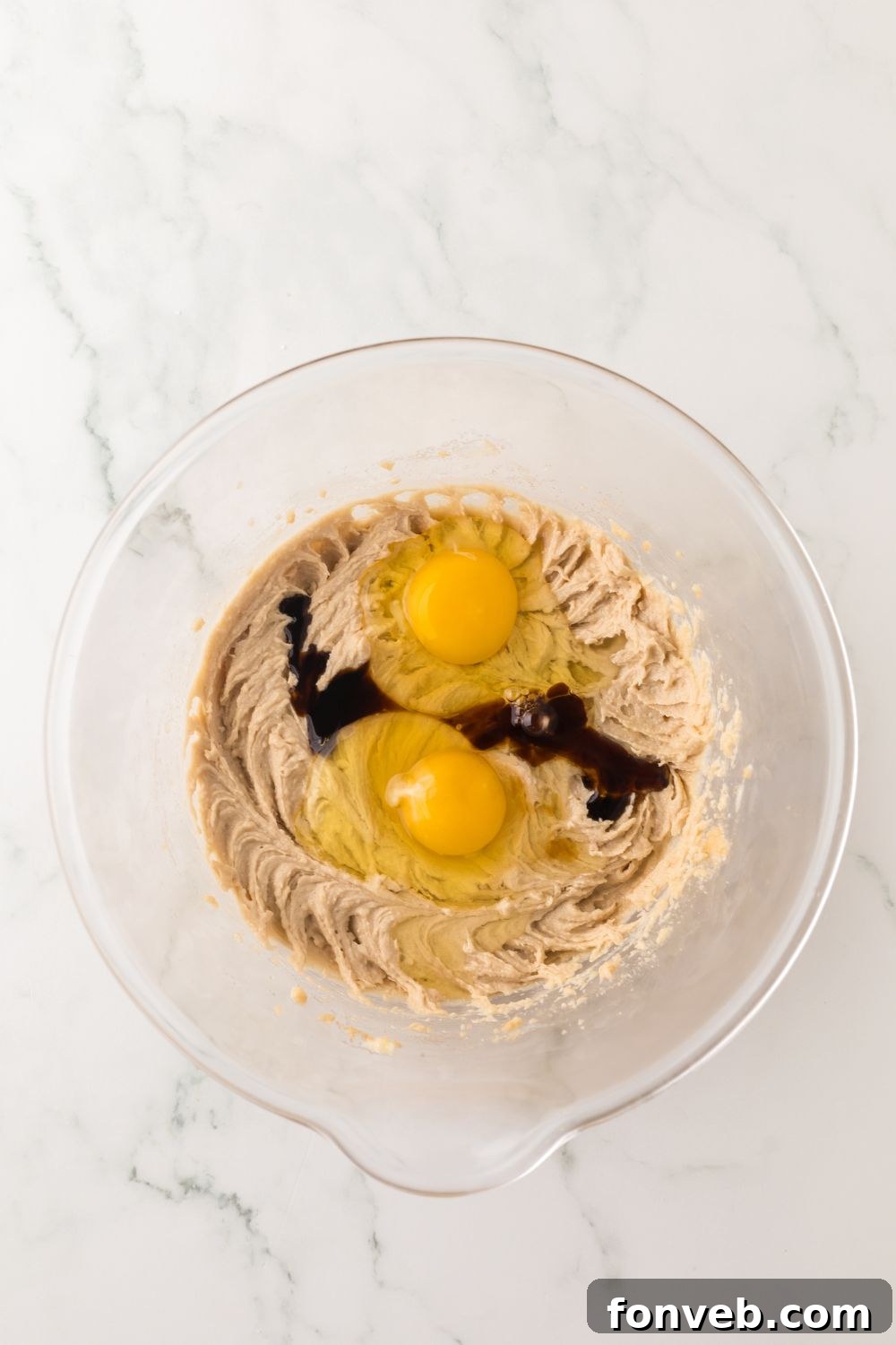 cheesecake cookie dough batter being mixed up with two eggs on top of cookie dough