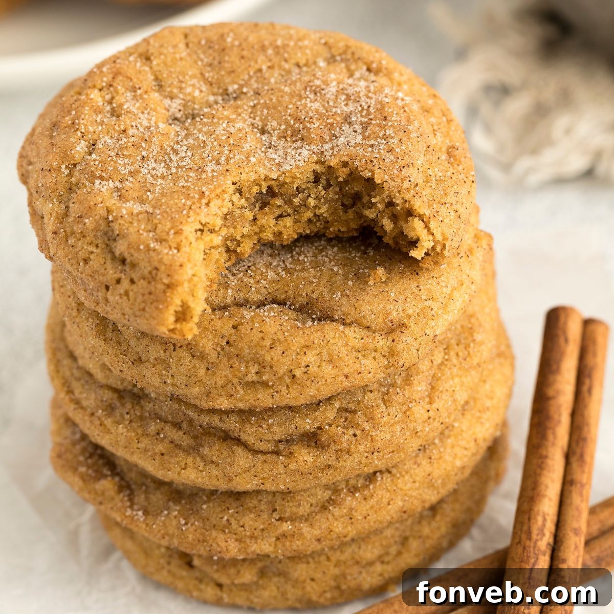 Spiced Pumpkin Snickerdoodle Cookies 2 Pumpkin Snickerdoodle Cookies stacked on top of one another on table with a bite taken out of the top one
