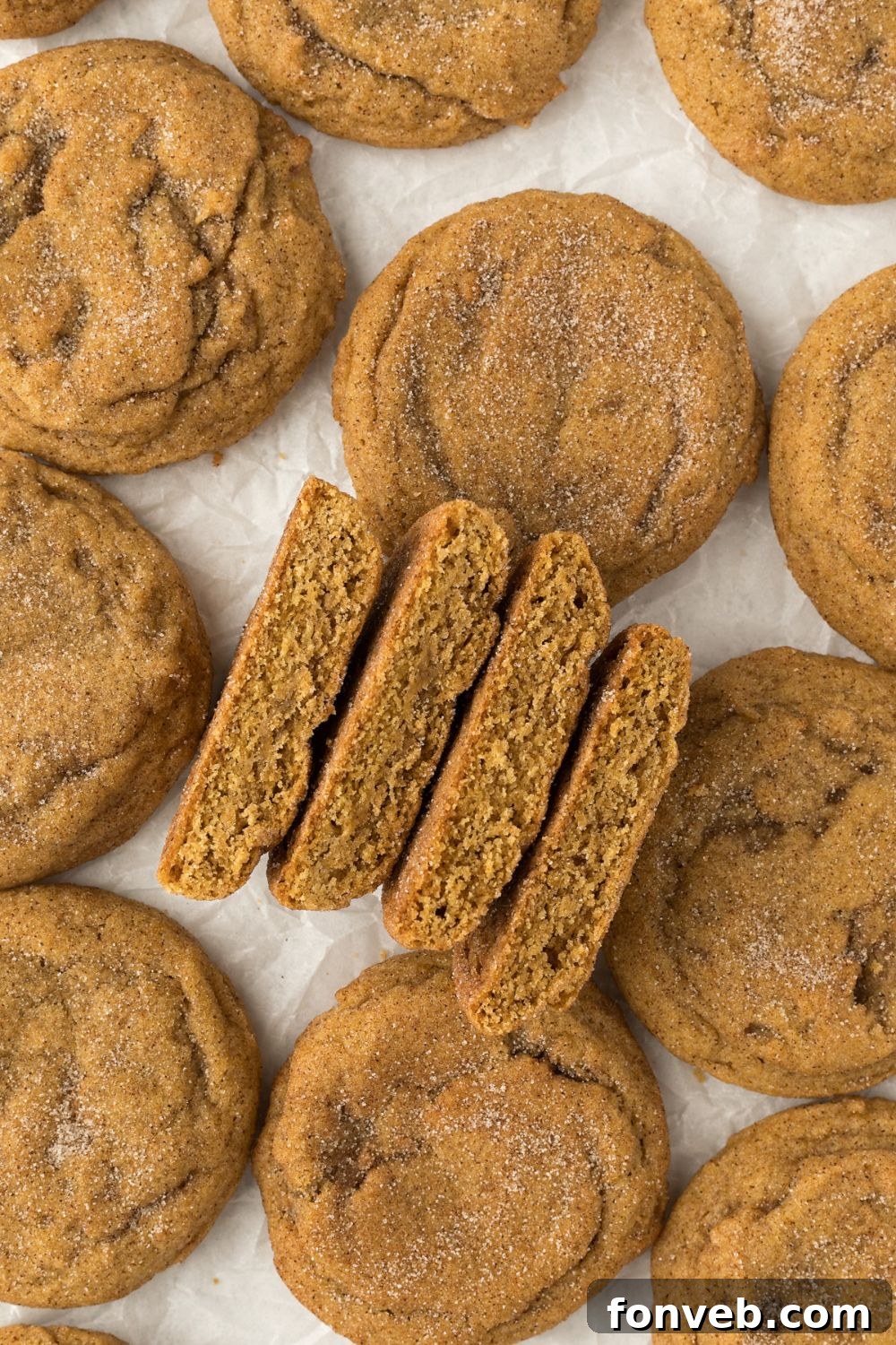 Spiced Pumpkin Snickerdoodle Cookies 4 Pumpkin Snickerdoodle Cookies on table with a few cut in half showing the center to see they are soft cookies