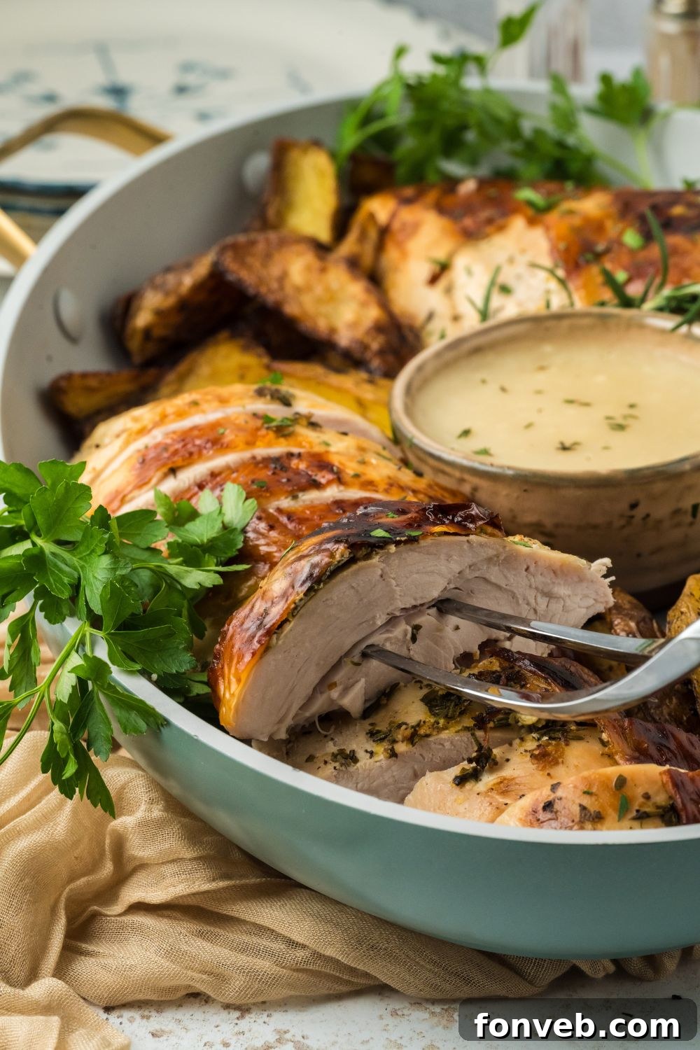 Sliced Roasted Turkey Breast in a bowl with a fork poking into a thicker slice to show how tender the turkey is