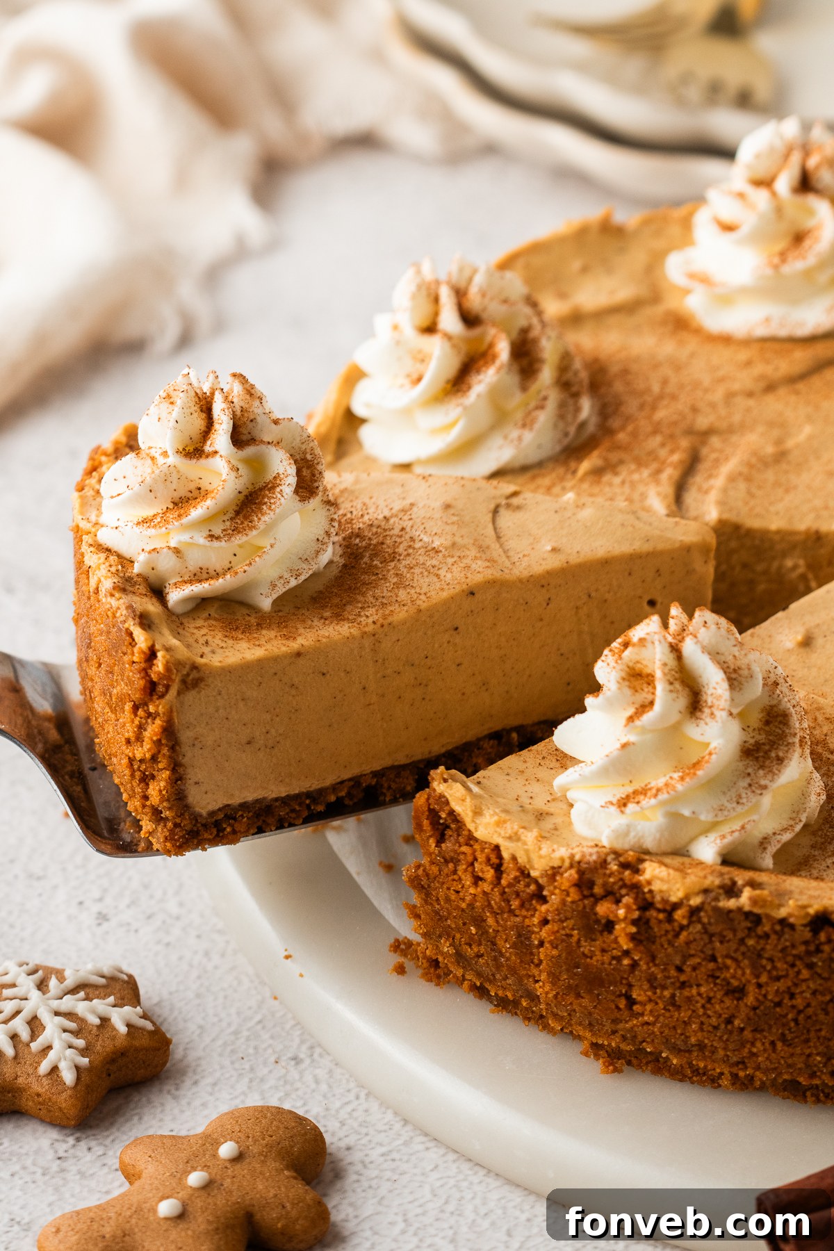 No Bake Gingerbread Cheesecake on a platter with one slice lifting out of the pie plate