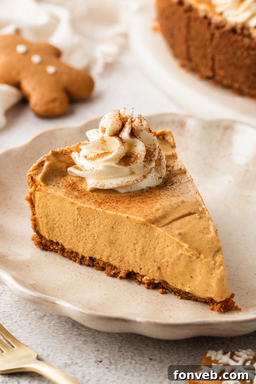 No Bake Gingerbread Cheesecake sliced on a white plate on table with gingerbread cookies around the table