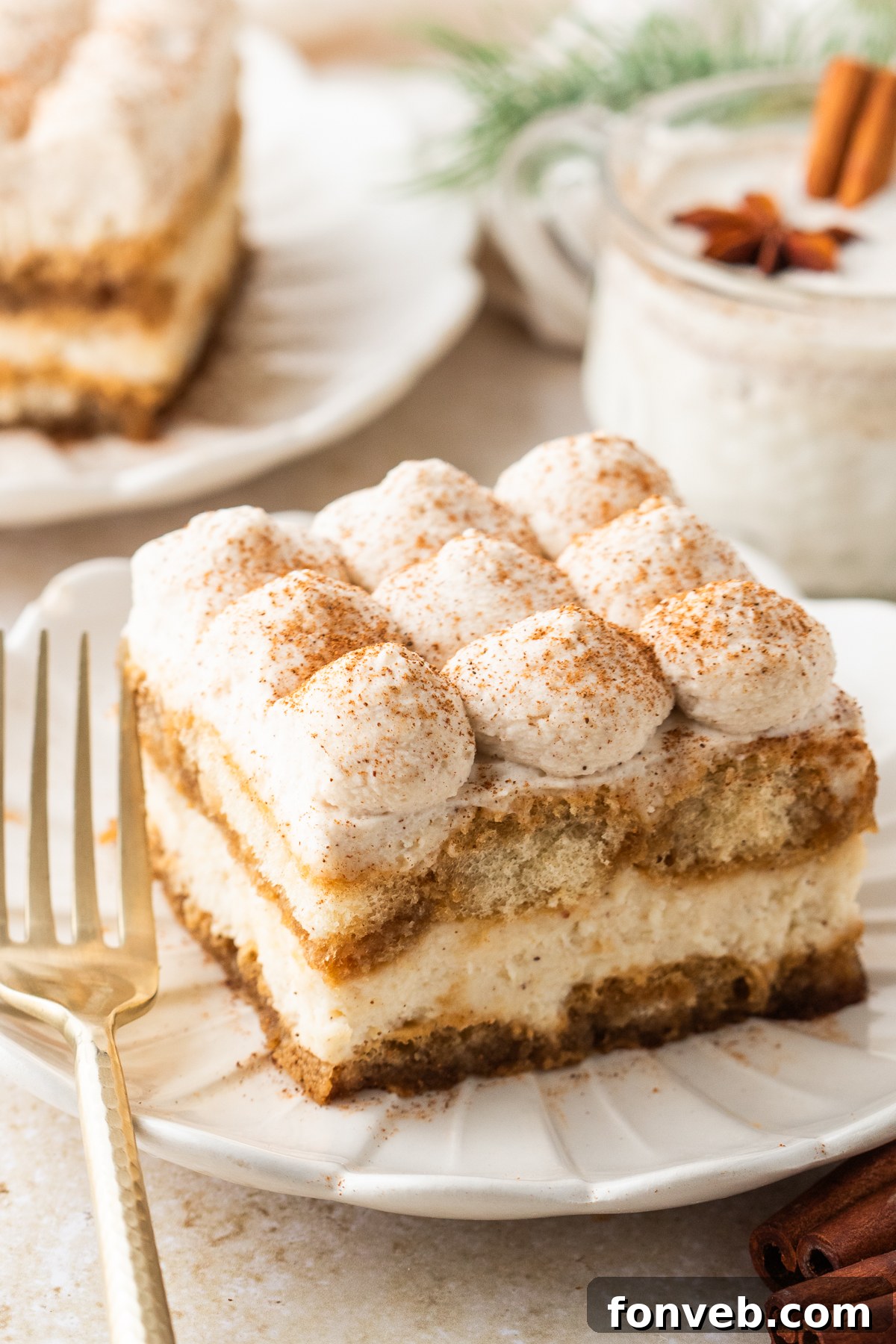 No Bake Eggnog Tiramisu sliced on white serving plates with a glass of eggnog behind the plate 
