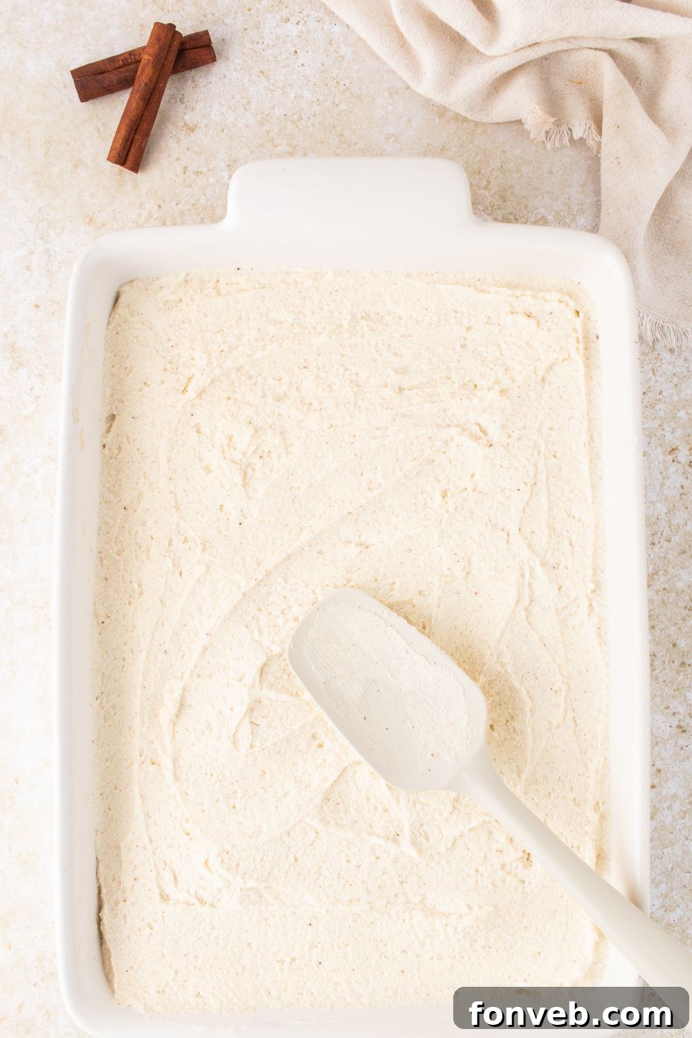 Eggnog Tiramisu being assembled with a spatula spreading around the creamy topping 